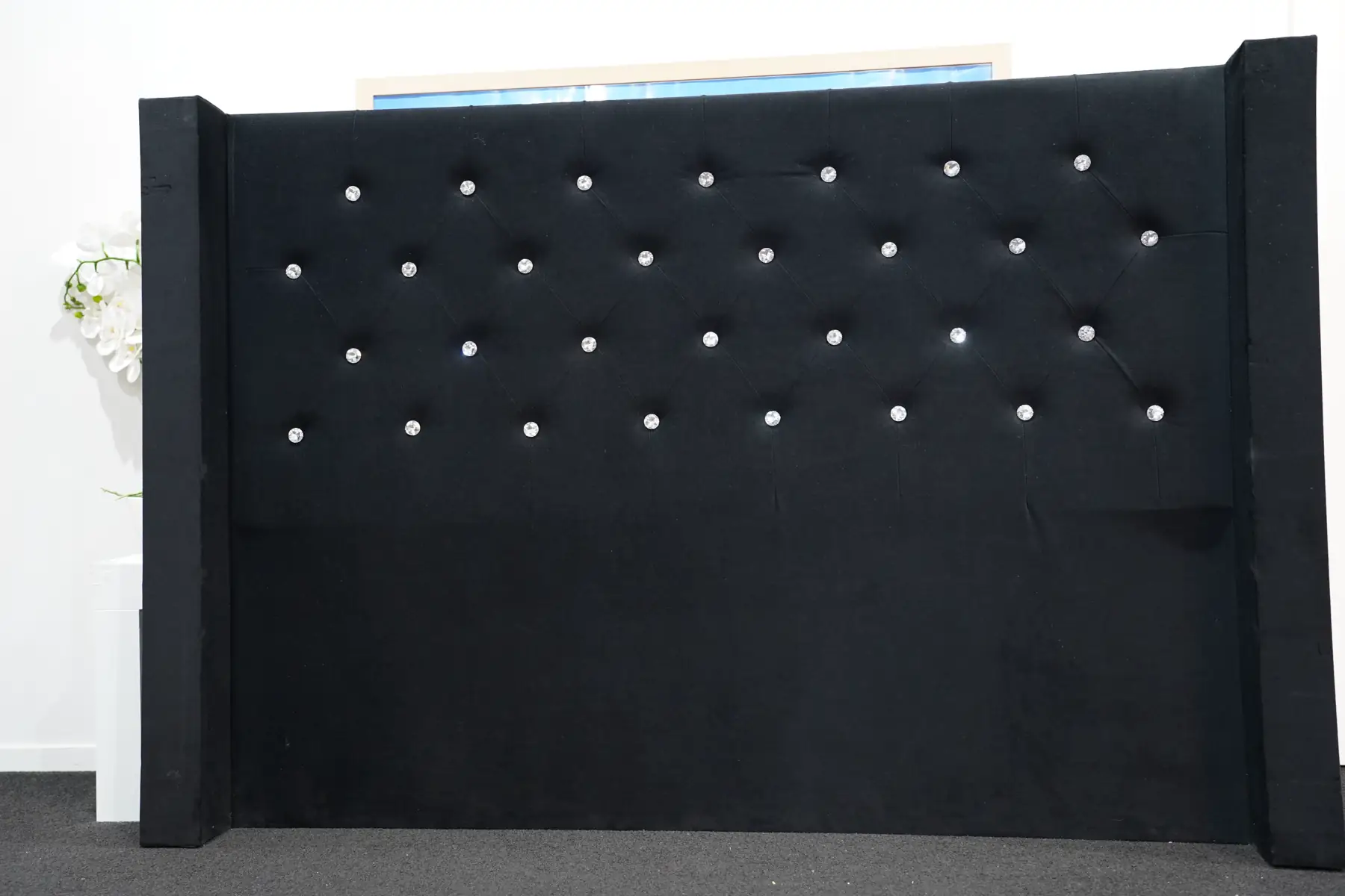 A wide black velvet headboard with crystal buttons and tall side wings.