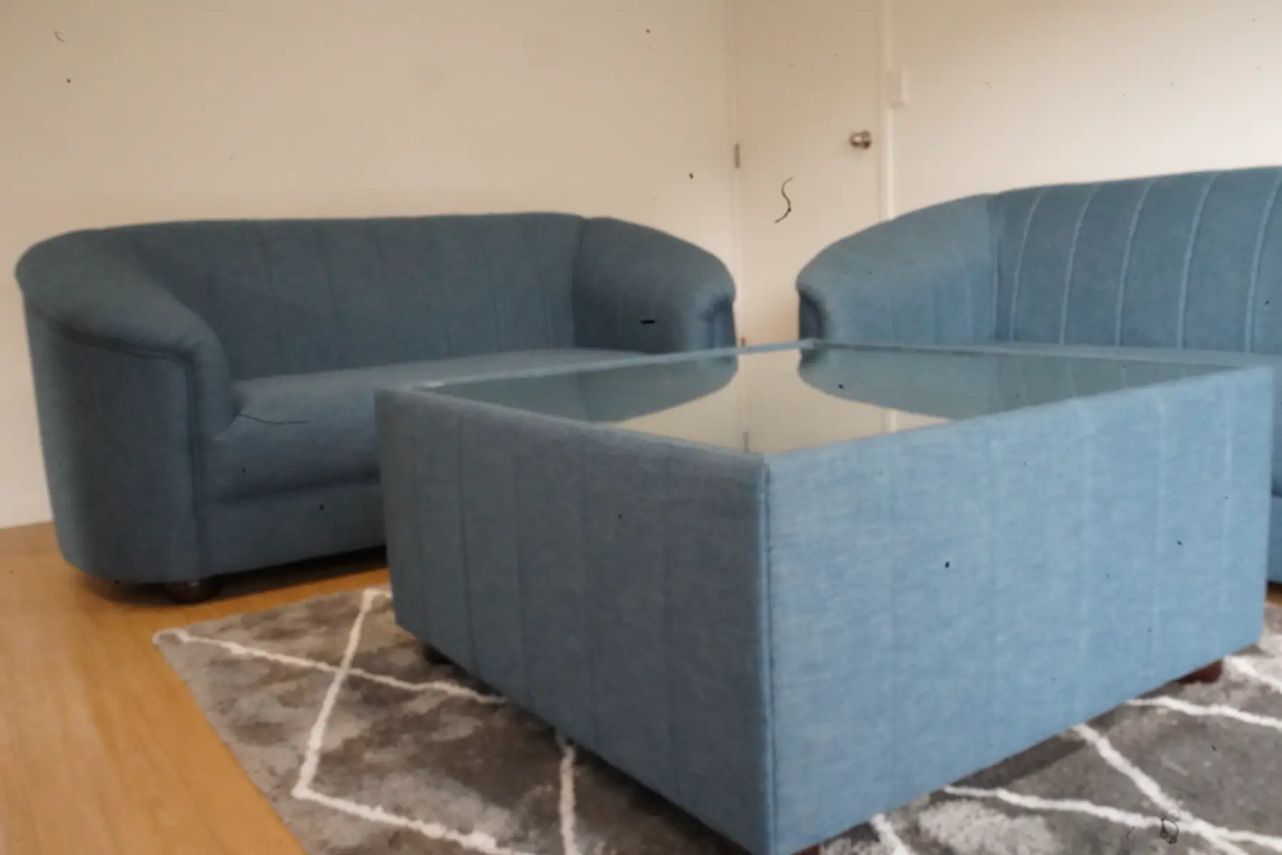 A blue-grey lounge suite with fluted backs and a matching glass-topped ottoman.