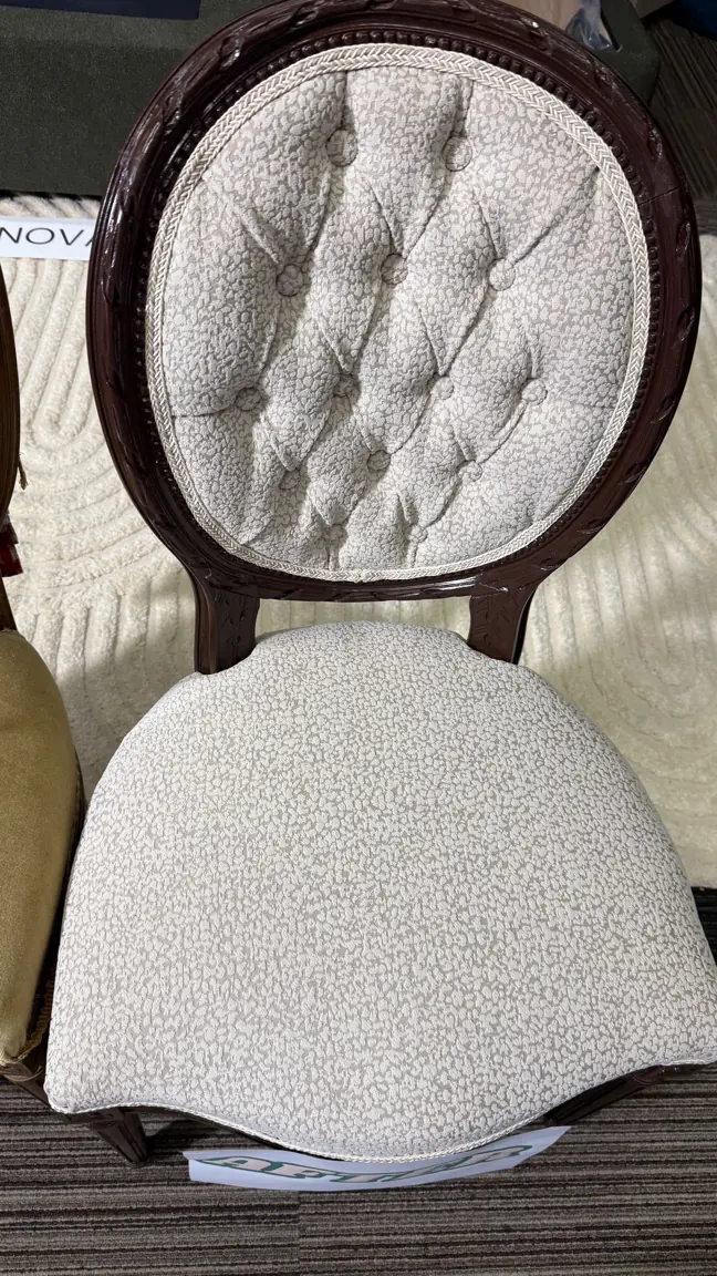 A carved cameo-back chair recovered in a pale textured cloth, buttoned into the oval back.