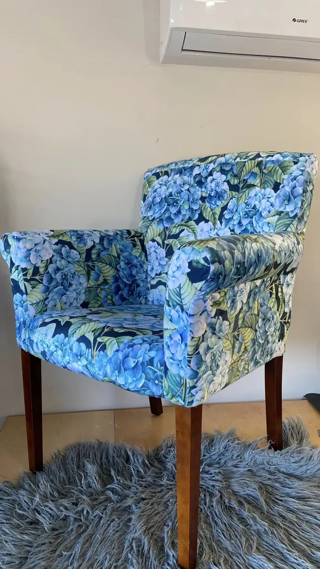 A tub chair recovered in a blue hydrangea print, on tapered timber legs.