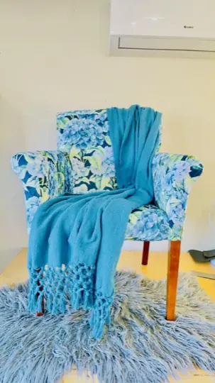A pair of chairs in blue hydrangea print with a teal throw across one arm.