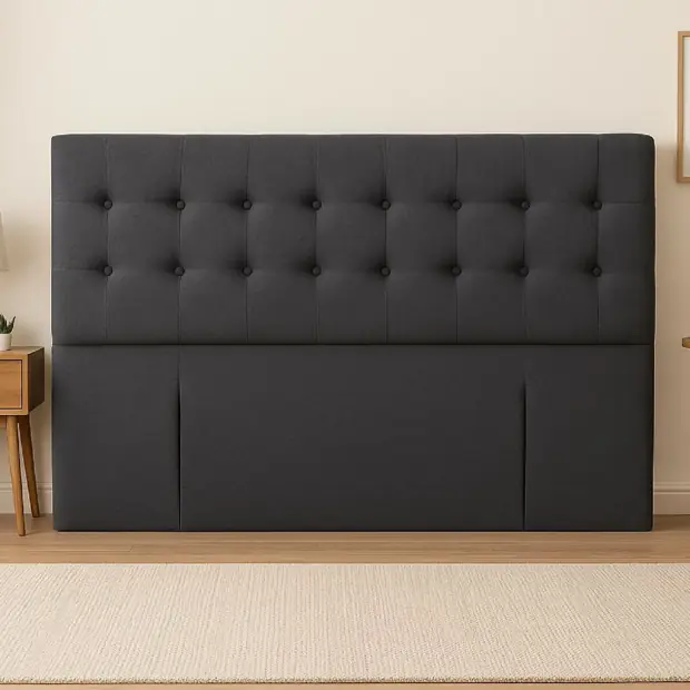 Charcoal grey padded bedhead against a plain wall, front view.