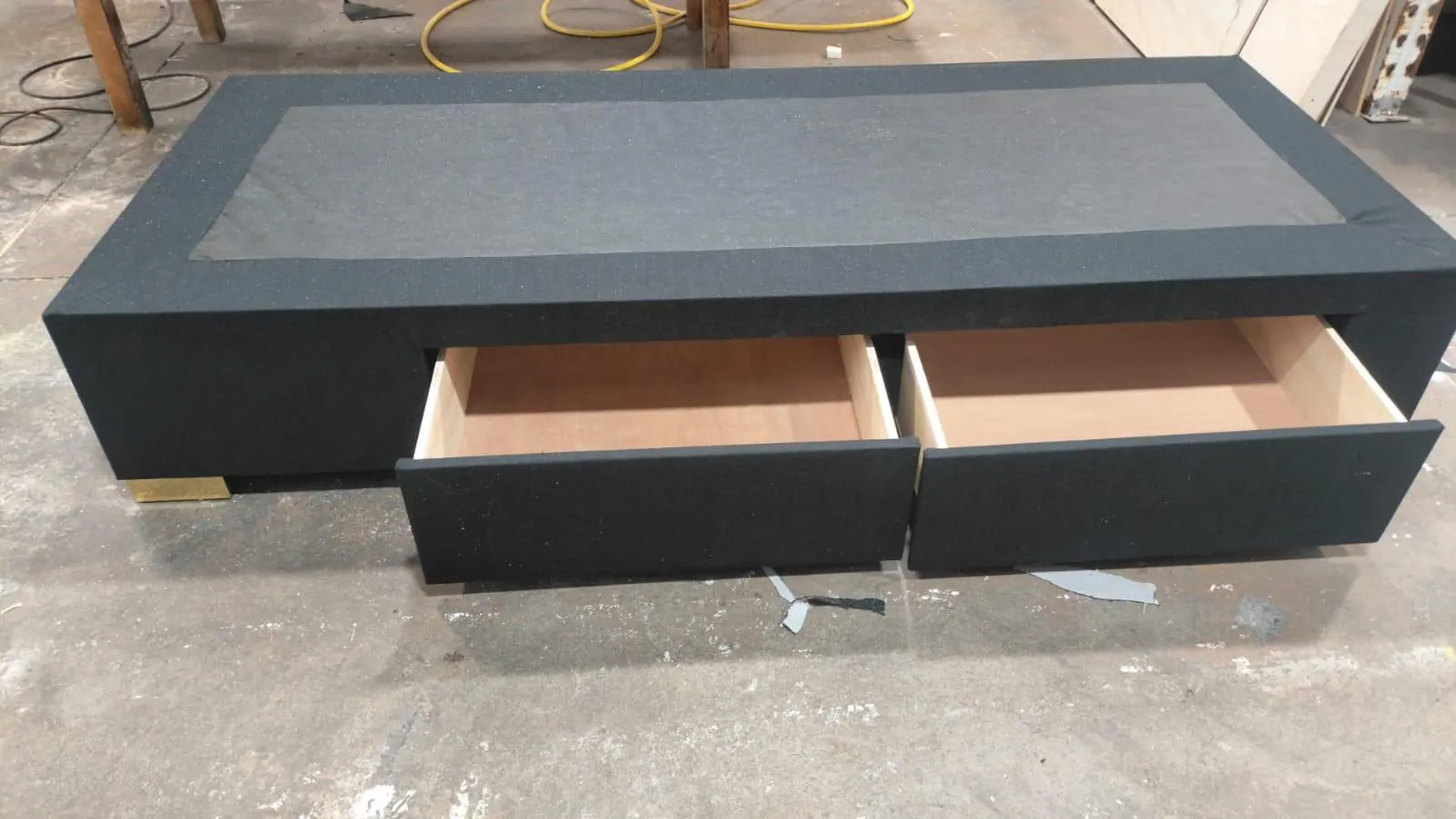 A charcoal bed base with two storage drawers pulled open, showing the timber drawer boxes.