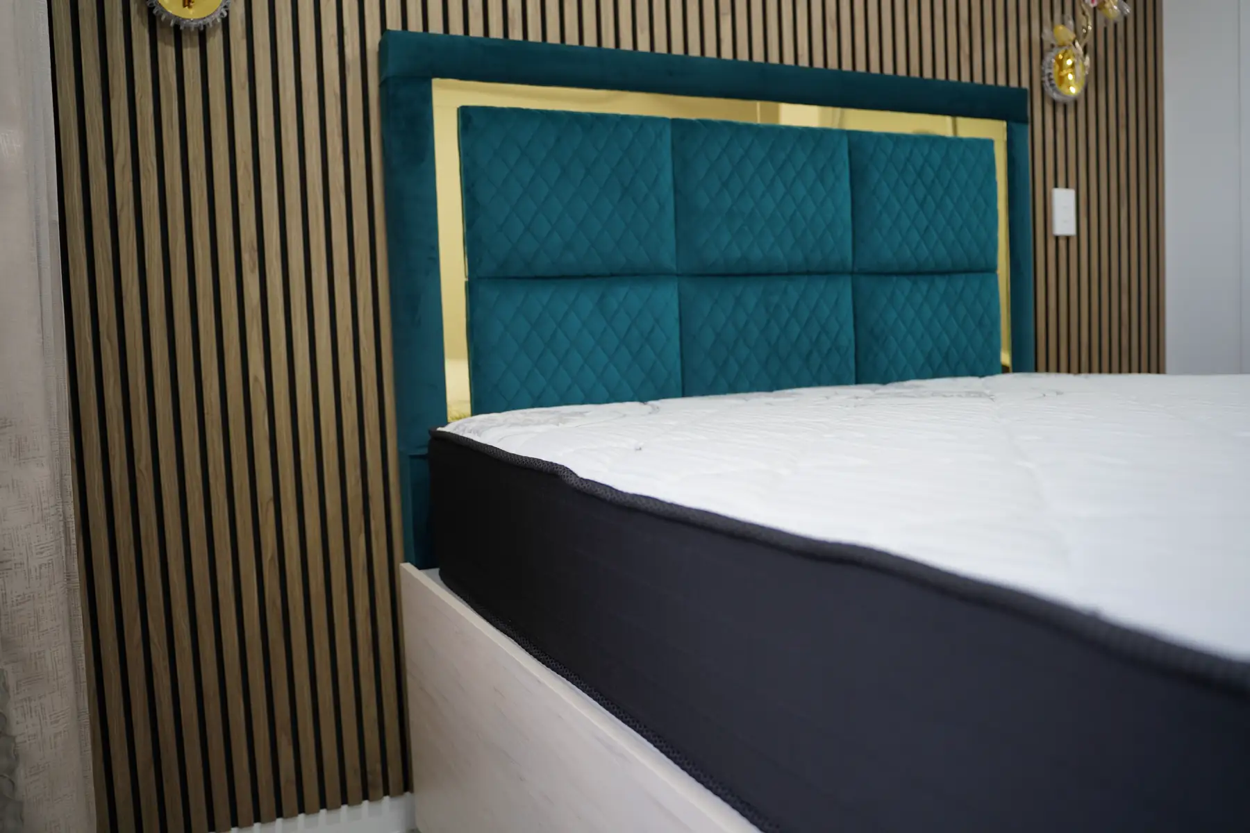 The teal velvet headboard above a made bed, gold frame catching the light from the side.